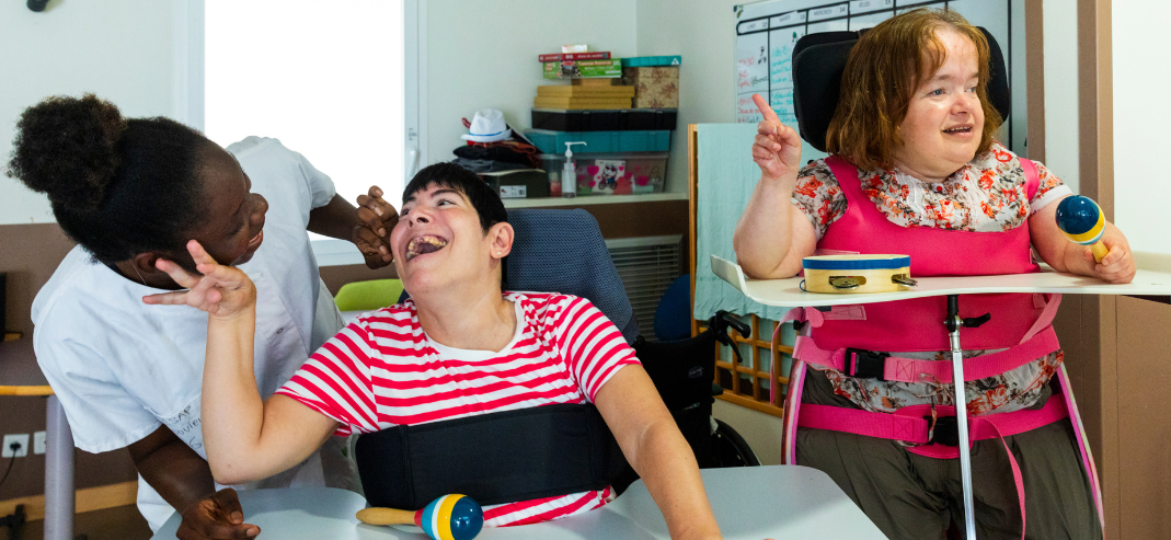 Deux personnes joyeuses en situation de handicap avec une accompagnante éducative et sociale